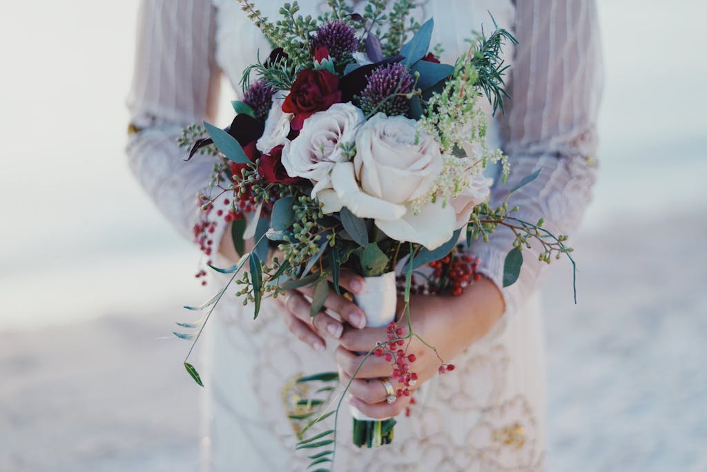 Close-up of a bride holding a beautiful bouquet at an outdoor wedding ceremony.